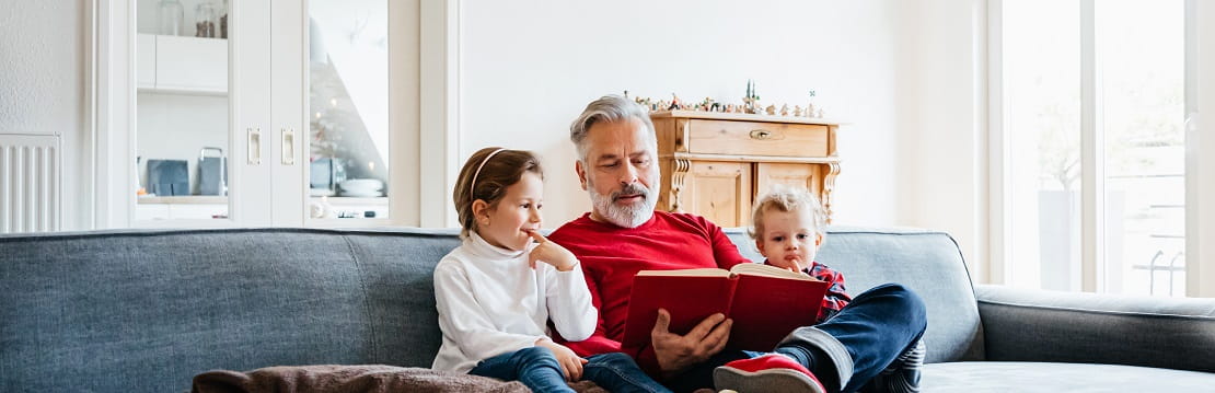 Man sits on the couch with his grandchildren. 