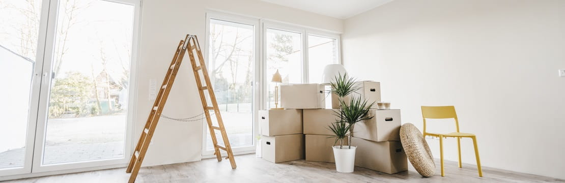 Moving boxes and ladder in empty room of a new home