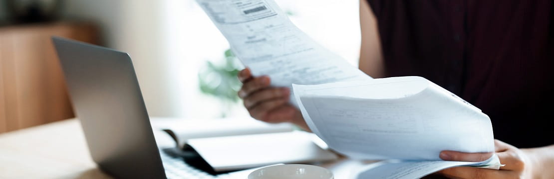 Woman looks at set of papers in front of her laptop